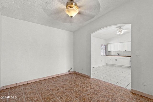 unfurnished living room with a textured ceiling, lofted ceiling, sink, and ceiling fan