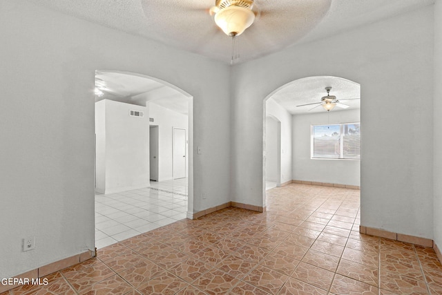 tiled empty room with ceiling fan and a textured ceiling