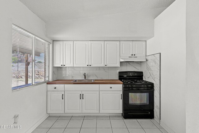 kitchen with black gas stove, white cabinets, lofted ceiling, decorative backsplash, and butcher block countertops