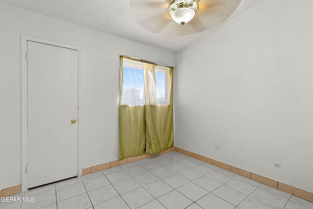 unfurnished room featuring a textured ceiling, light tile patterned floors, and ceiling fan