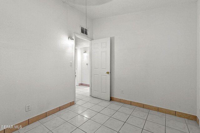 unfurnished room with a textured ceiling and light tile patterned floors