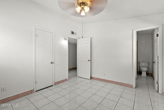 unfurnished bedroom featuring connected bathroom, ceiling fan, light tile patterned floors, and a textured ceiling