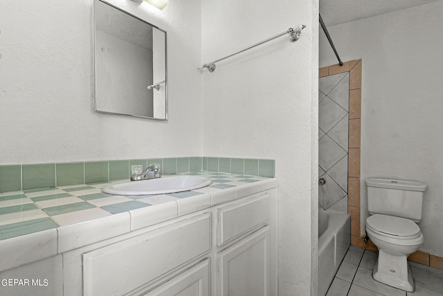 full bathroom with tile patterned flooring, a textured ceiling, tiled shower / bath combo, vanity, and toilet