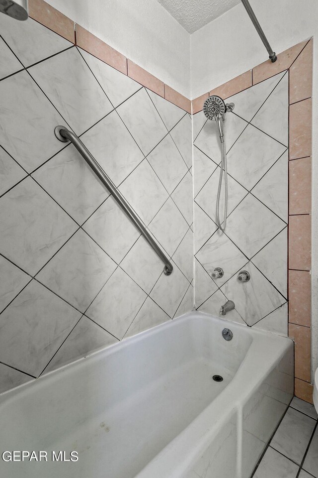 bathroom with tile patterned flooring, a textured ceiling, and tiled shower / bath combo