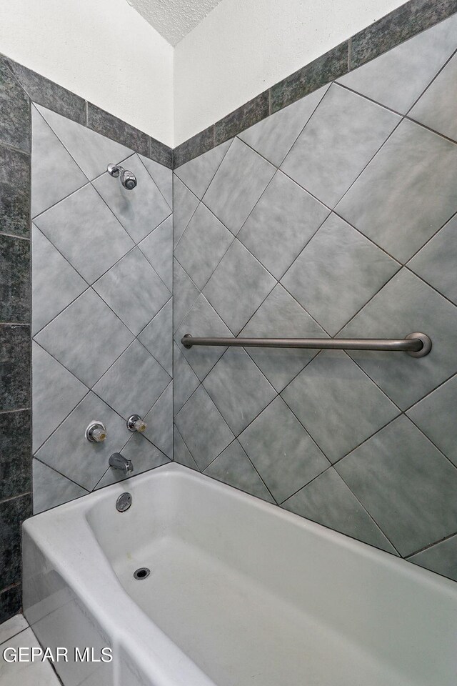 bathroom featuring a textured ceiling and tiled shower / bath combo