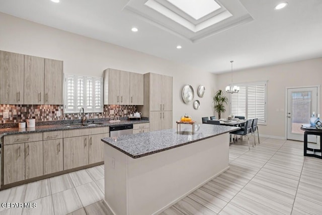 kitchen with dark stone countertops, backsplash, a center island, sink, and a chandelier