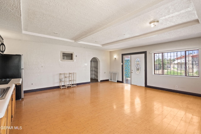 unfurnished living room featuring a textured ceiling, beamed ceiling, and hardwood / wood-style floors