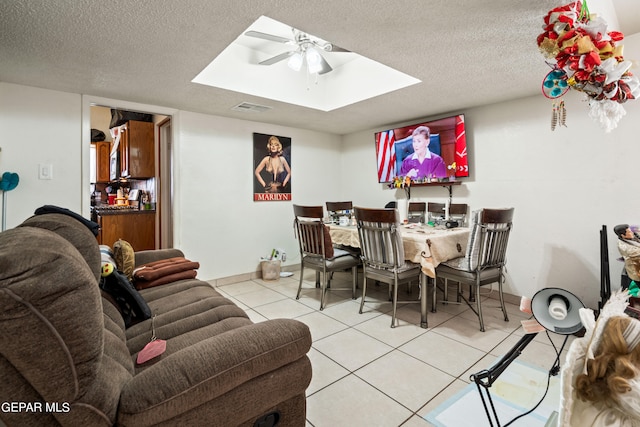 living room with a textured ceiling, light tile patterned flooring, and ceiling fan