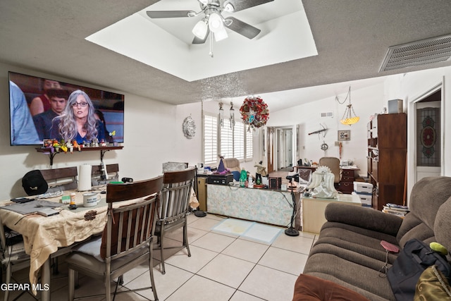 dining room featuring a textured ceiling, light tile patterned floors, a tray ceiling, and ceiling fan