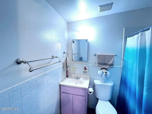 bathroom featuring tile walls, curtained shower, vanity, and toilet