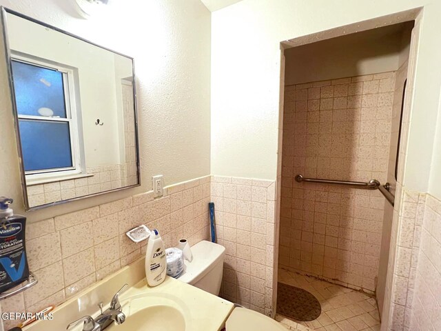 bathroom featuring vanity, tile walls, and toilet