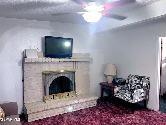 living room with a brick fireplace, ceiling fan, carpet floors, and a textured ceiling