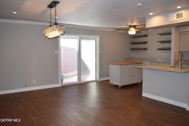 kitchen with ceiling fan, white cabinets, decorative light fixtures, dark hardwood / wood-style floors, and crown molding