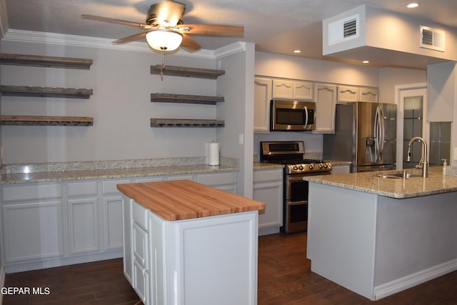 kitchen featuring a kitchen island, sink, stainless steel appliances, and white cabinetry