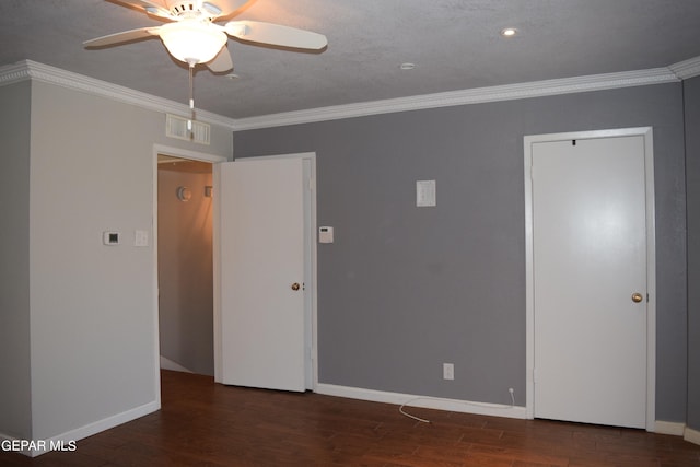 empty room with a textured ceiling, ornamental molding, dark wood-type flooring, and ceiling fan