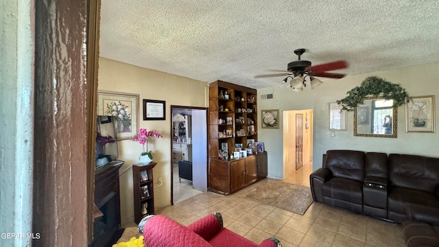 living room with a textured ceiling, light tile patterned floors, and ceiling fan