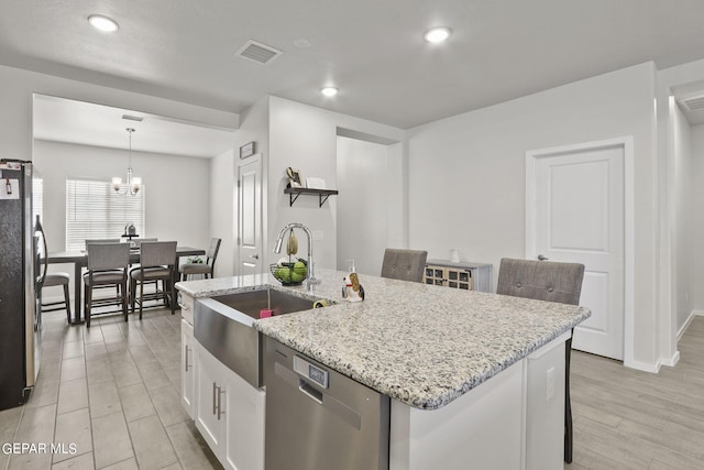 kitchen featuring white cabinets, an island with sink, pendant lighting, appliances with stainless steel finishes, and a notable chandelier