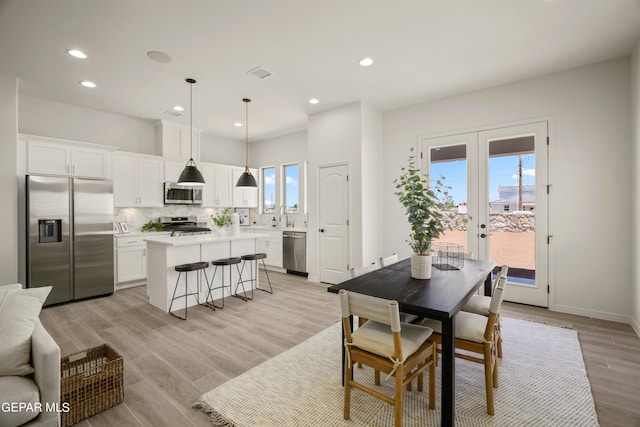 dining space featuring a water view, light hardwood / wood-style floors, french doors, and sink