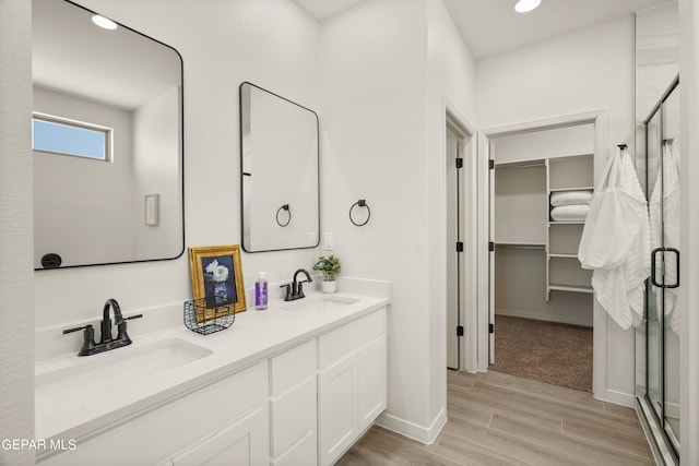 bathroom with wood-type flooring, vanity, and a shower with door