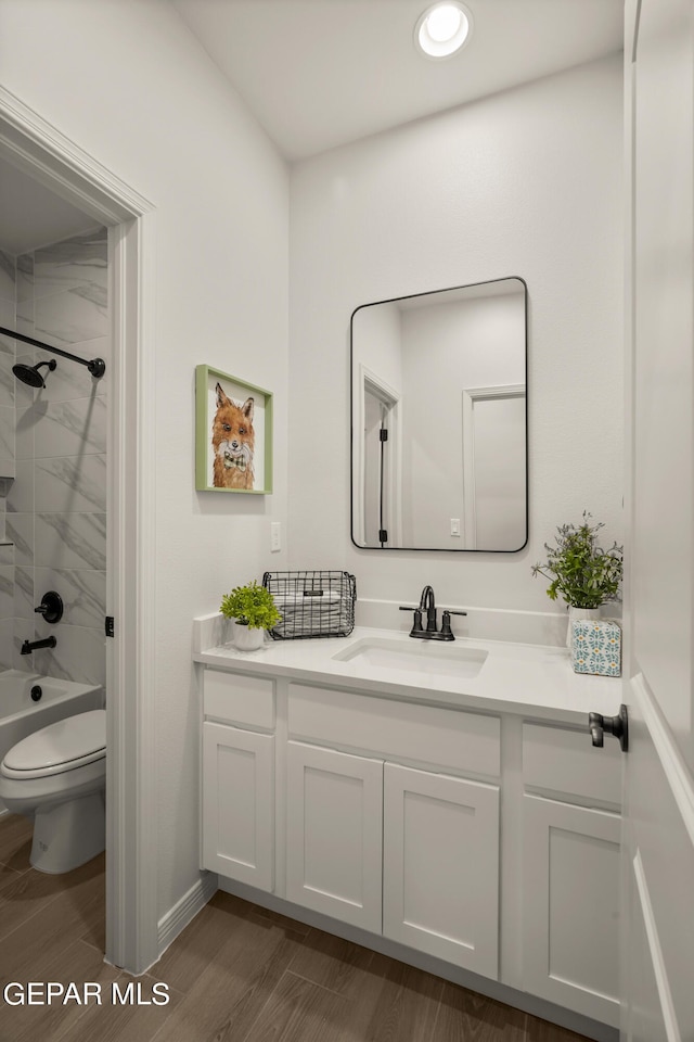 full bathroom featuring tiled shower / bath, vanity, toilet, and hardwood / wood-style flooring