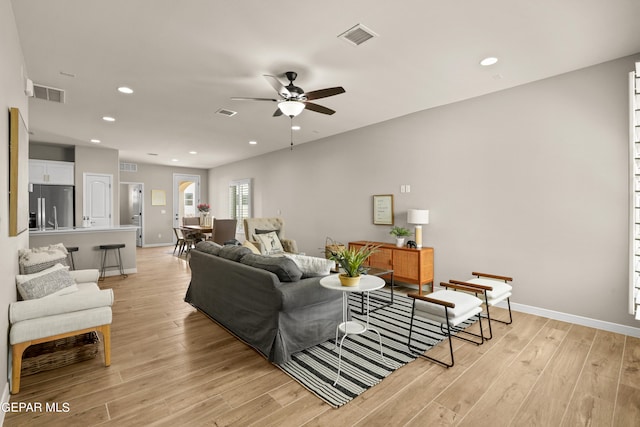 living room with ceiling fan and light hardwood / wood-style flooring