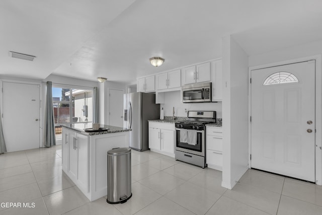 kitchen featuring light stone counters, white cabinetry, a kitchen island, stainless steel appliances, and light tile patterned floors