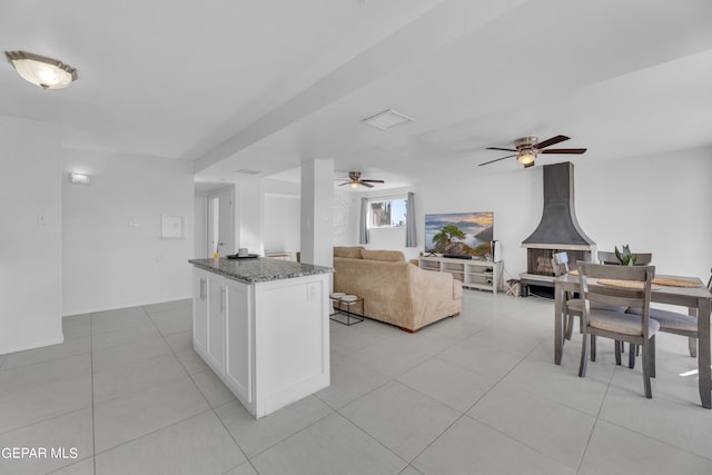 kitchen featuring ceiling fan, white cabinets, a wood stove, and stone countertops