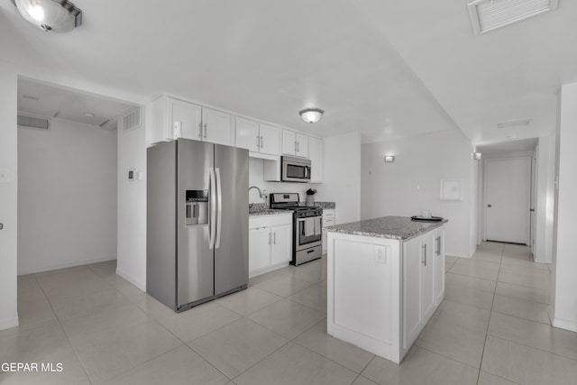 kitchen featuring appliances with stainless steel finishes, a center island, white cabinetry, and light stone countertops