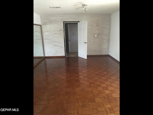 unfurnished room with dark parquet floors and a textured ceiling