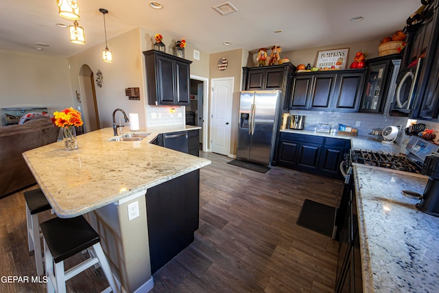 kitchen featuring sink, kitchen peninsula, decorative backsplash, stainless steel appliances, and dark hardwood / wood-style flooring