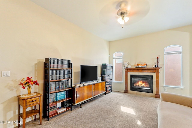 carpeted living room featuring a tile fireplace and ceiling fan