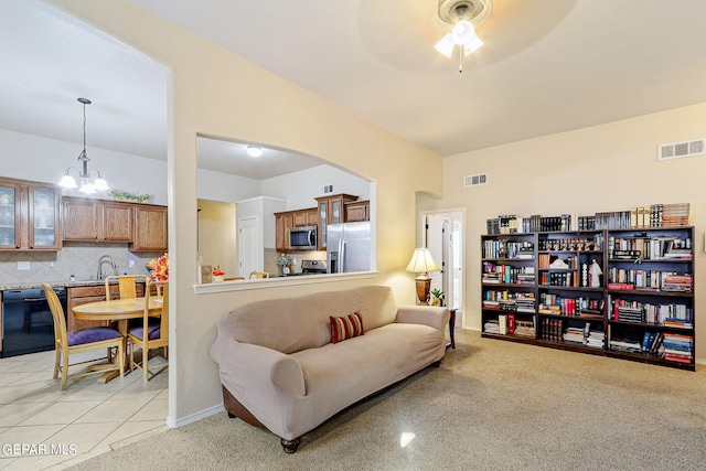 living room featuring ceiling fan with notable chandelier, light tile patterned floors, and sink