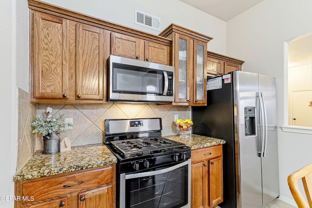 kitchen featuring appliances with stainless steel finishes, light stone counters, and tasteful backsplash