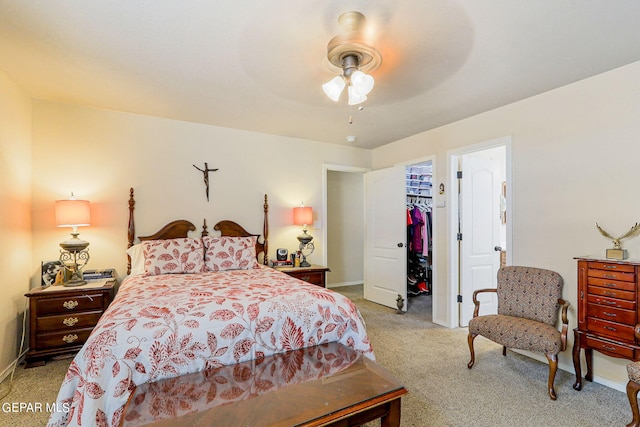 bedroom with ceiling fan, light colored carpet, a closet, and a walk in closet