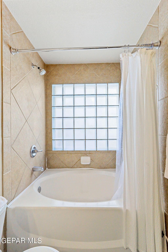 bathroom featuring shower / bath combination with curtain, a textured ceiling, and toilet