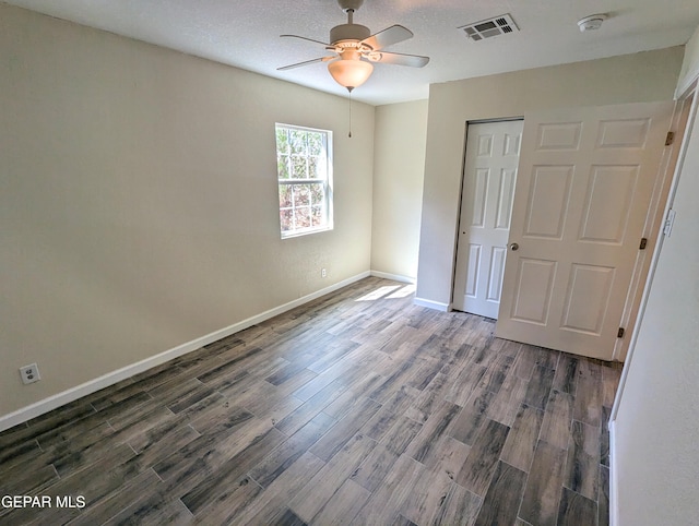 unfurnished bedroom featuring a closet, ceiling fan, dark hardwood / wood-style floors, and a textured ceiling