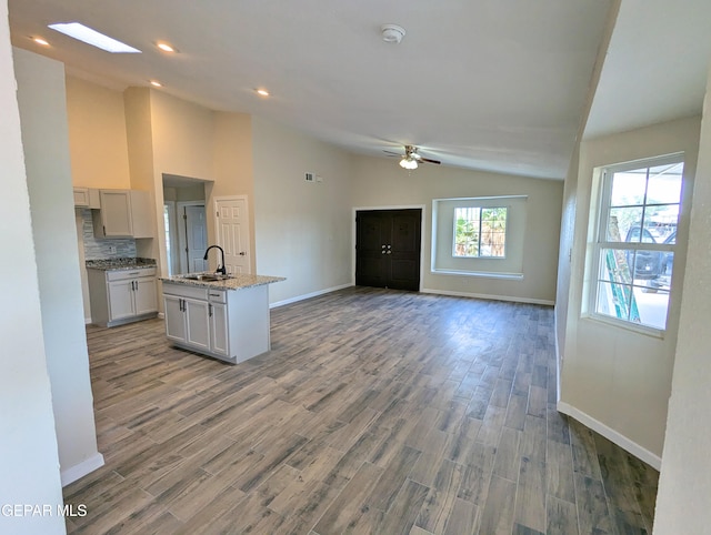 kitchen with hardwood / wood-style floors, ceiling fan, a kitchen island with sink, and sink