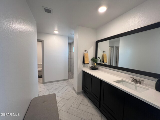 bathroom featuring a shower, vanity, and toilet