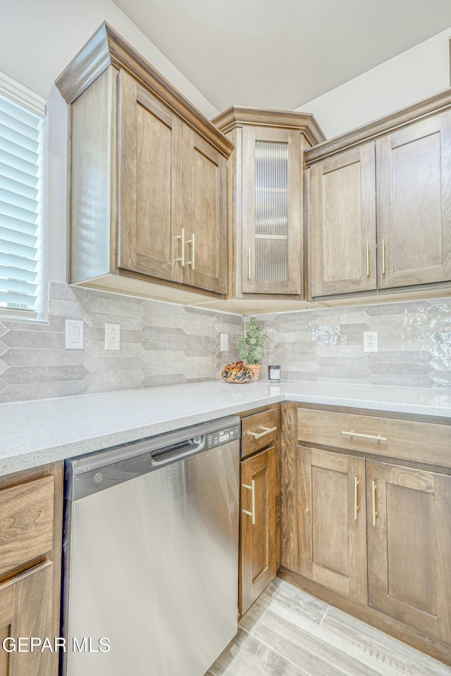 kitchen featuring dishwasher, light wood-type flooring, tasteful backsplash, and light stone counters