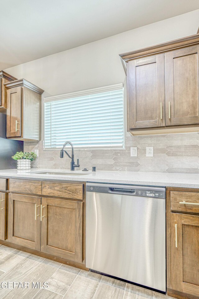 kitchen with backsplash, light stone counters, sink, light hardwood / wood-style flooring, and dishwasher