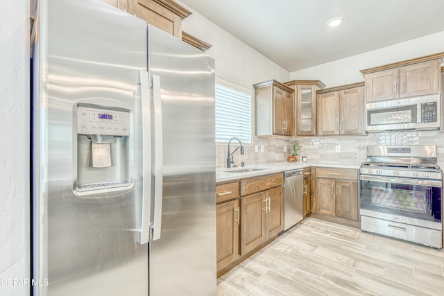 kitchen with backsplash, sink, stainless steel appliances, and light hardwood / wood-style flooring