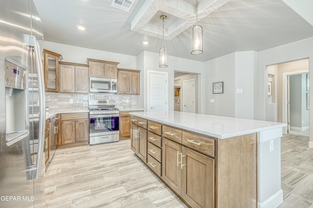 kitchen featuring decorative backsplash, light wood-type flooring, stainless steel appliances, decorative light fixtures, and a kitchen island