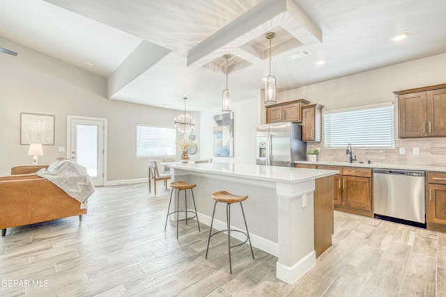 kitchen featuring light wood-type flooring, stainless steel appliances, pendant lighting, a center island, and a breakfast bar area