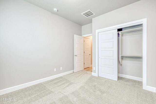 unfurnished bedroom with light carpet and a closet