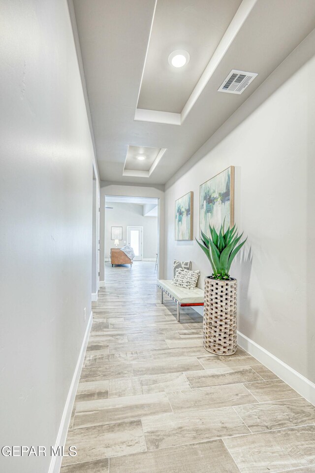 hallway featuring a raised ceiling and light wood-type flooring