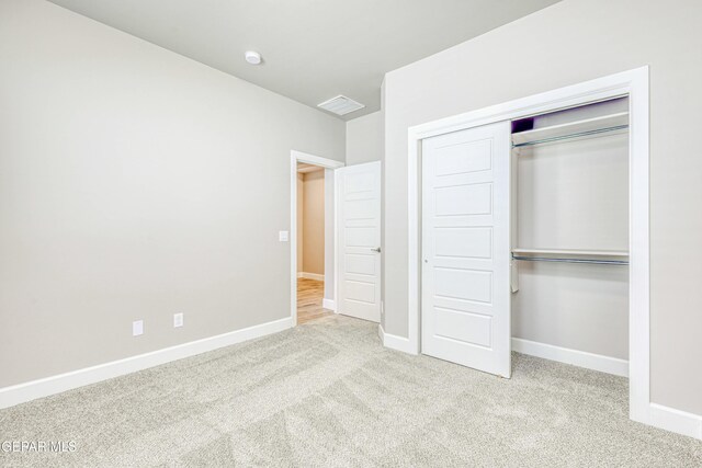 unfurnished bedroom with light carpet and a closet