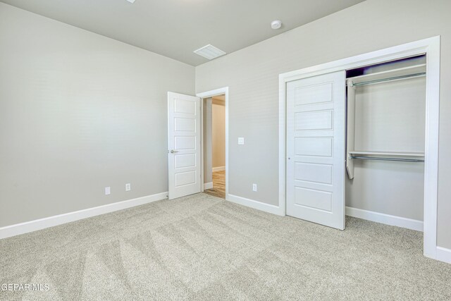 unfurnished bedroom with a closet and light colored carpet