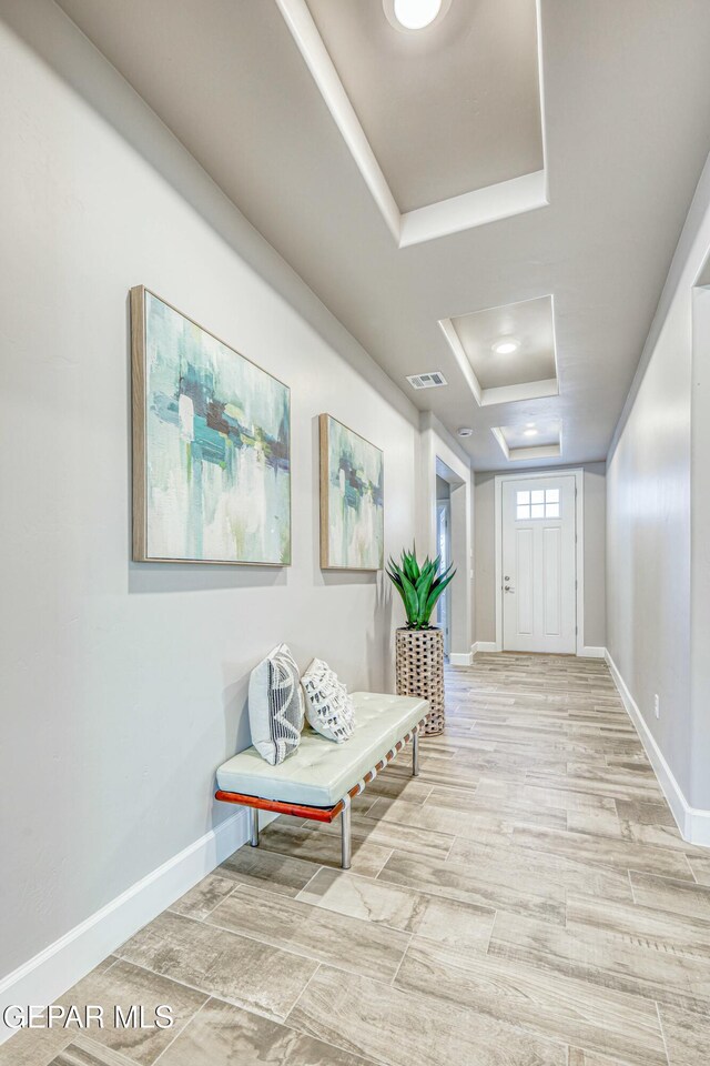 hall with a tray ceiling and light hardwood / wood-style flooring