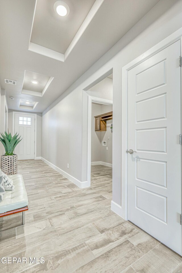 interior space featuring a tray ceiling and light hardwood / wood-style floors