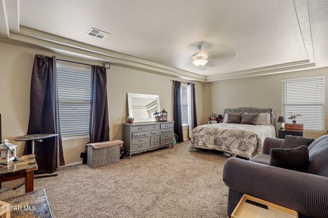 carpeted bedroom featuring a textured ceiling, a tray ceiling, and ceiling fan